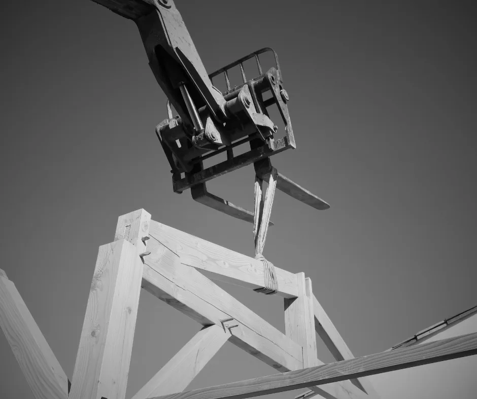Levage d’éléments de charpente bois par engin de chantier lors de la mise en œuvre structurelle